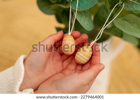 Two Easter decorative eggs on ropes on eucalyptus in the palms of a child