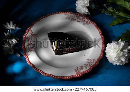 Plate with slice of tasty homemade chocolate cake on table dramatic light