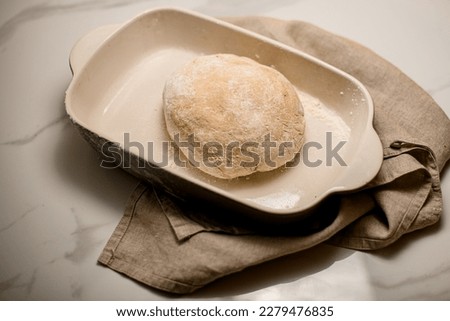 close-up top view of raw dough in a ceramic baking dish on the table. Preparation of the bread process