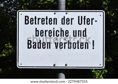 Metal German Sign Beside Public Bathing Pool Translated as 'Entering the shore areas and bathing are prohibited' 
