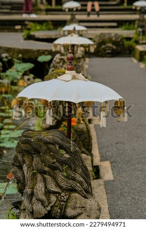 Statues wIth white umbrella by the pond of Saraswati Temple in Ubud Bali Indonesia.