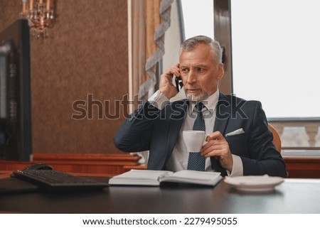 Male hotelier works at a computer and talking phone while sitting in his office in hotel Royalty-Free Stock Photo #2279495055