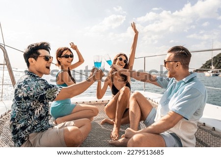 Group of diverse friends drink champagne while having a party in yacht. Attractive young men and women hanging out, celebrating holiday vacation trip while catamaran boat sailing during summer sunset. Royalty-Free Stock Photo #2279513685