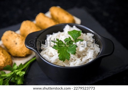 Bolinhos de bacalhau, very famous in Portuguese gastronomy. Fried dumpling, cod dumpling, fish, salted cod fritters, bacalao bunuelos. Codfish cake served with white rice on a dark background.