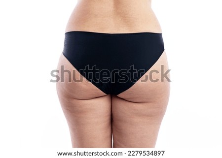 Overweight woman with cellulite in black shorts. Back view. Isolated on a white background. Close-up.