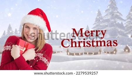 Composite image of happy young woman in santa hat embracing gift by christmas greeting. christmas festivity, tradition and winter holiday.