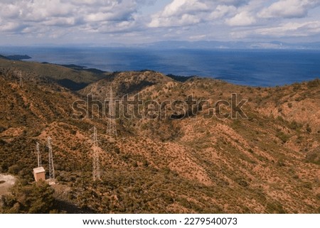 Aerial shot of electricity pylons with connected cables on mountains