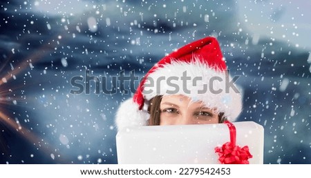 Composition of woman in santa hat with christmas present over snowy background, copy space. christmas festivity, vector and winter holiday.
