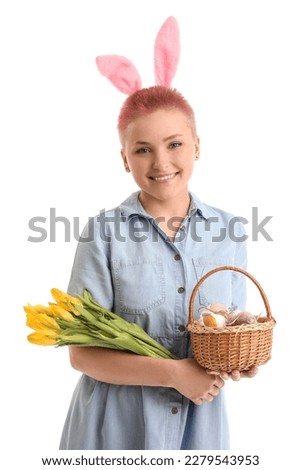 Young woman with bunny ears, tulips and basket of Easter eggs on white background