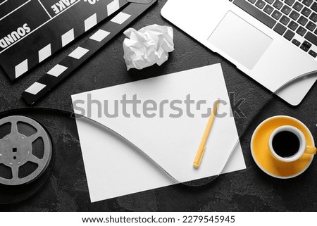 Blank paper sheet with movie clapper, film reel and cup of coffee on dark background