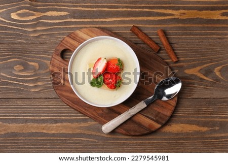 Bowl of tasty semolina porridge with strawberry on wooden background Royalty-Free Stock Photo #2279545981