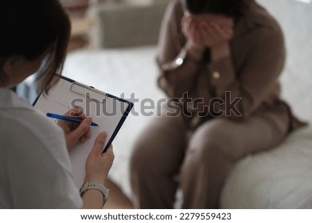 patient makes progress towards healing and recovery as she talks with her therapist about her struggles. psychologist takes notes during the therapy session to help her patient Royalty-Free Stock Photo #2279559423