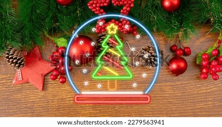 Overhead view of illuminated neon christmas tree symbol over decorations on table. celebration and decoration.