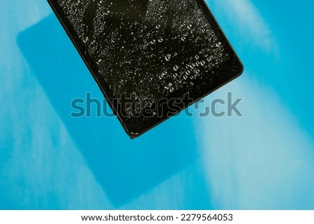 Wet smashed tablet on blue background