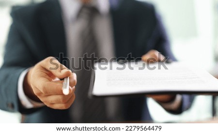 Manager holding out paper document on clipboard and pen for signing closeup Royalty-Free Stock Photo #2279564479