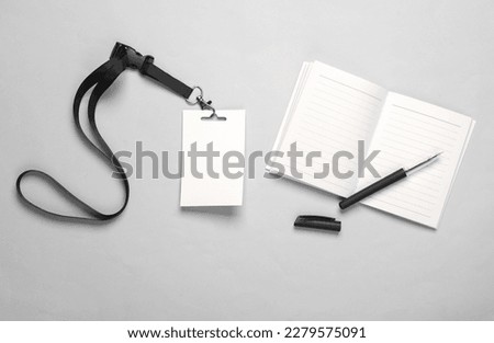 Notebook and Empty white ID card badge mockup on gray background. Staff identity name tag. Space for text and design.