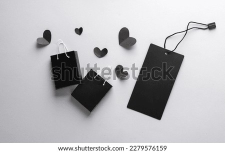 Sale, creative layout. Black shopping bags and hearts, price tag on gray background. Black Friday. Top view