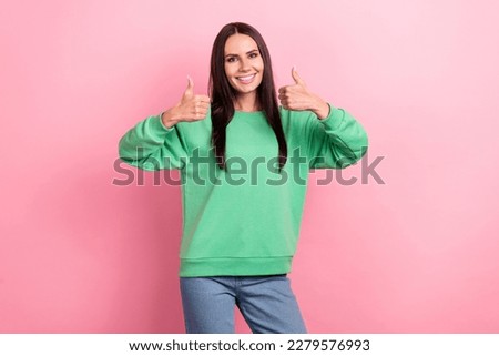 Photo of optimistic satisfied woman with long hairstyle dressed green sweatshirt showing thumbs up isolated on pink color background
