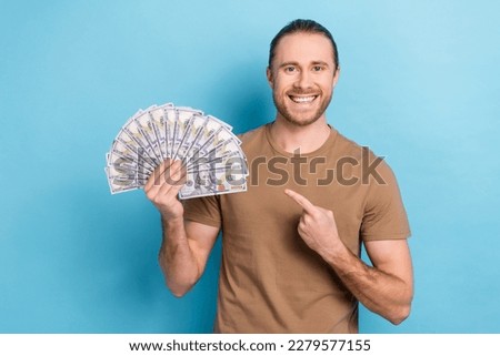 Photo of young funny millionaire entrepreneur hold cash banknotes dollars direct finger his income prize jackpot isolated on blue color background
