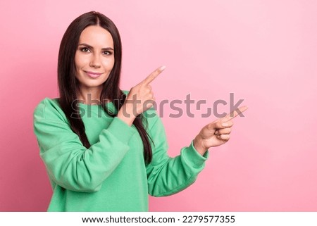Portrait of confident latin lady wear green sweatshirt directing fingers empty space save cashback ebank promo isolated on pink color background