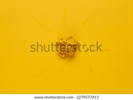 Paper sun with rays on a yellow background.