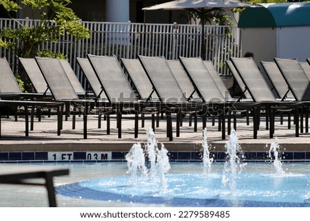 Rows of empty lounge chairs surrounded the shallow end of a swimming pool.