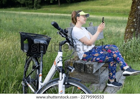A young girl in a white T-shirt by bicycle takes a photo