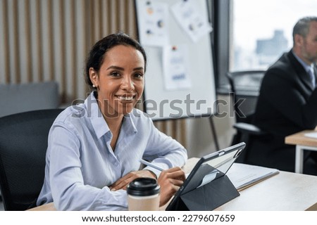 Portrait of Latino beautiful business woman smile while work in office. Attractive professional female employee worker in formal wear sit on table at workplace, use laptop computer and look at camera. Royalty-Free Stock Photo #2279607659