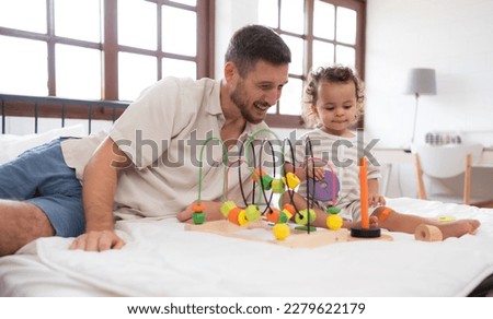 Father with little girl have fun playing with your new toys in the bedroom together. Toys that enhance children's thinking skills.