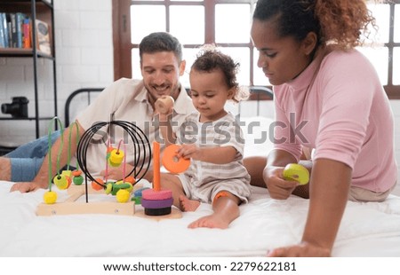 Parents with little girl have fun playing with your new toys in the bedroom together. Toys that enhance children's thinking skills.