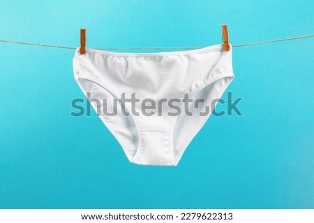 white washed women's panties made of cotton with clothespins hanging on a rope on a blue background Royalty-Free Stock Photo #2279622313