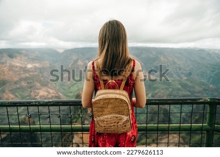 girl taking picture on phone in waimea canyon, kauai, hawaii. High quality photo