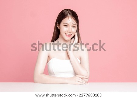 Young Asian woman long hair with natural makeup on face have plump lips and clean fresh skin on isolated pink background. Portrait of cute female model in studio. Facial treatment, Cosmetology.