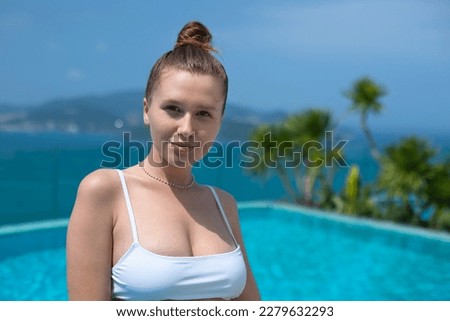 Young beautiful woman lay on sunbed near swimming pool at summer sunny day, enjoy vacation at tropical resort and smile in bikini, sunbathing, tanning 