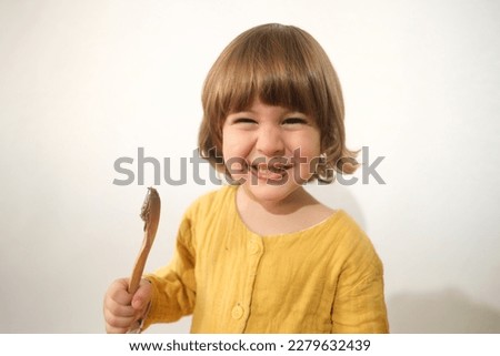 boy eats chocolate with wooden spoon