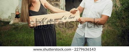 Husband and wife hold wooden vintage textured plate with love inscriptions in their hands. Image for your creative design or illustrations.