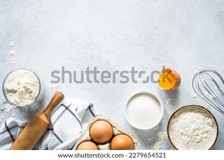 Baking background ingredients. Flour, sugar, eggs and others at light stone table. Top view with copy space. Royalty-Free Stock Photo #2279654521