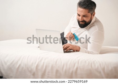 Joyful gentleman making online payment from portable computer