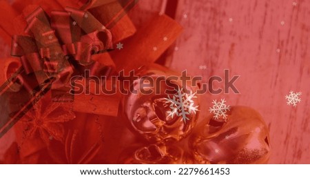 Image of christmas snowflakes falling over cinnamon sticks and decorations. christmas, tradition and celebration concept digitally generated image.