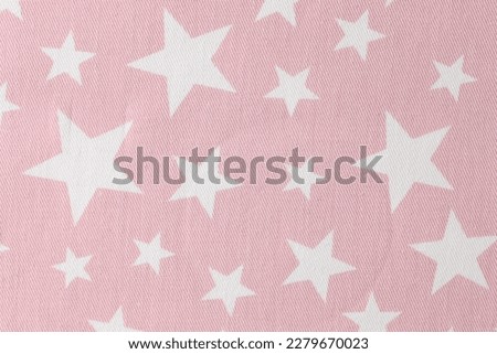 Pink cotton fabric with star pattern for children clothes upper view. Gentle textile material with white ornament. Sewing industry Royalty-Free Stock Photo #2279670023