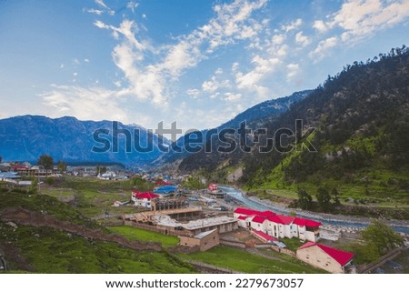 The landscape picture of houses in the mountains of Kalam, Pakistan. The image captures a serene and tranquil setting that is surrounded by lush green forests and lake.
