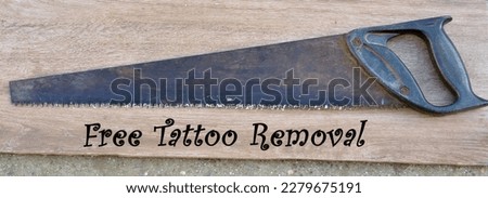 Old rusty hand saw with the inscription "Free Tattoo Removal" Royalty-Free Stock Photo #2279675191