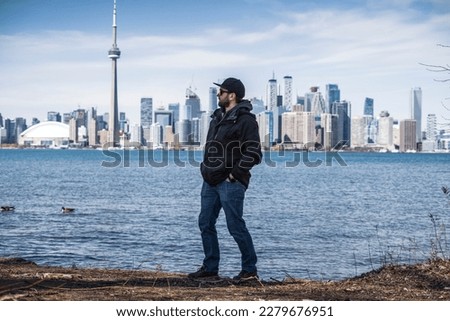 man poses on the coast of toronto island park with toronto skyline on background