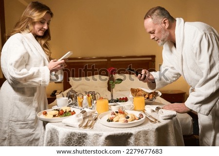 Man and a woman are taking pictures of their breakfast