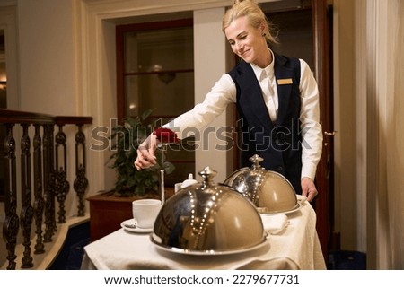 Caring waitress in uniform delivers food to a hotel room Royalty-Free Stock Photo #2279677731