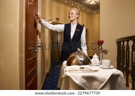 Pleasant waitress knocking on the door of the hotel room Royalty-Free Stock Photo #2279677739