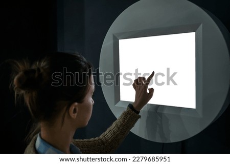 Woman hand using white blank interactive touchscreen display of electronic multimedia kiosk in dark room - scroll, touch - close up. Mock up, copyspace, template and technology concept Royalty-Free Stock Photo #2279685951