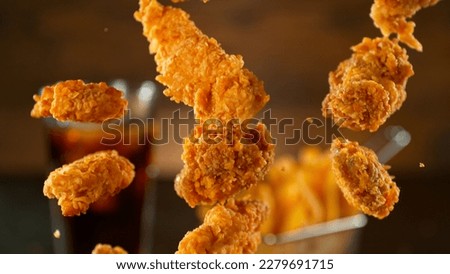Freeze Motion Shot of Flying Fresh Fried Chicken Wings or Strips, Close-up Royalty-Free Stock Photo #2279691715