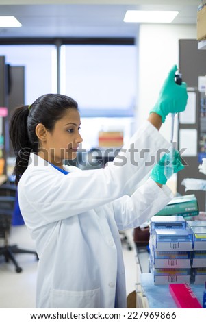 Closeup portrait, young scientist in white labcoat and blue nitrile latex gloves doing experiments in lab, academic sector. Research and development Royalty-Free Stock Photo #227969866