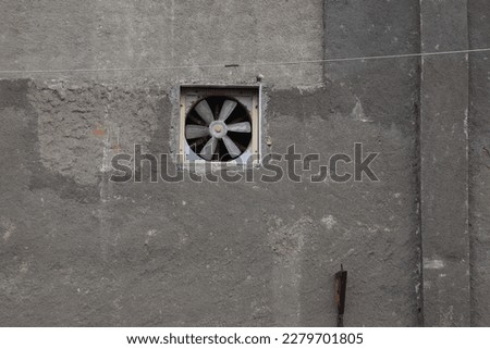 Old wall ventilation fan on uneven cement wall
